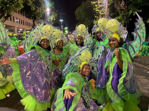 Travelers in elaborate green and purple winged Carnival costumes
